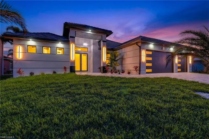 Modern home with a garage, driveway, a front yard, and stucco Block Structure