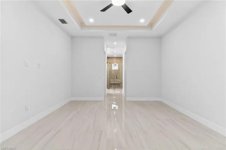 Primary bedroom featuring a ceiling fan, a raised ceiling, and recessed lighting