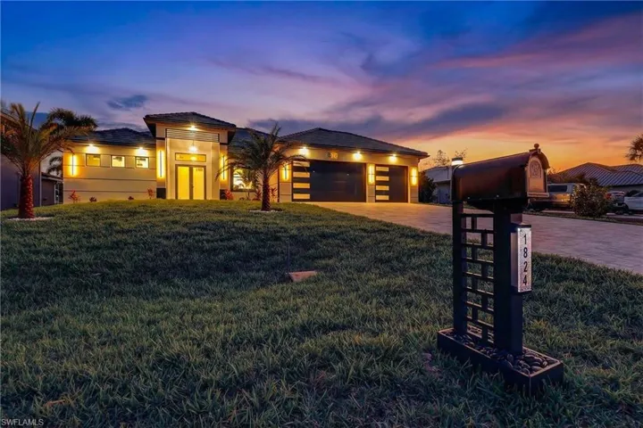 View of front of property featuring a lawn, decorative driveway, stucco Block Structure, and an attached garage