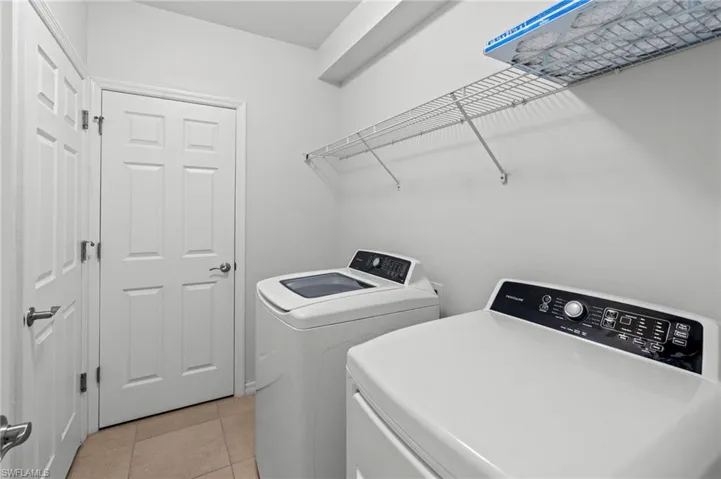 Laundry room featuring light tile patterned flooring and washing machine and dryer