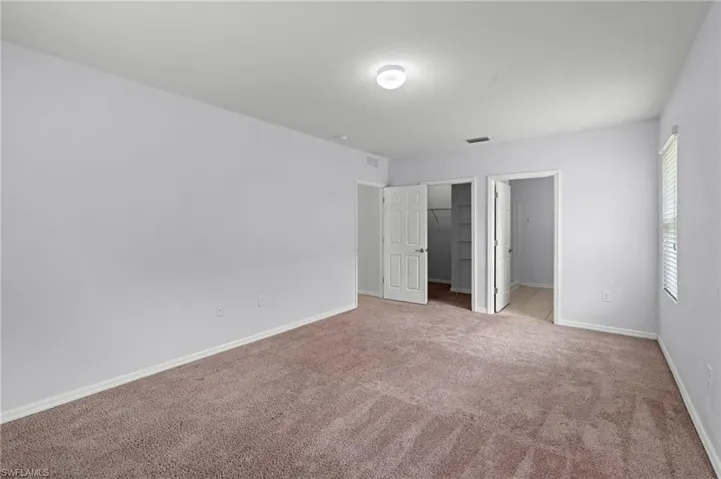Unfurnished bedroom with a spacious closet and carpet