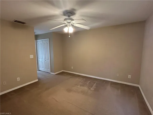 Carpeted spare room featuring a ceiling fan and baseboards