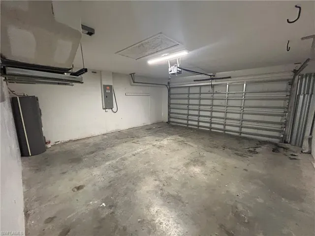 Garage with electric panel, water heater, and a garage door opener
