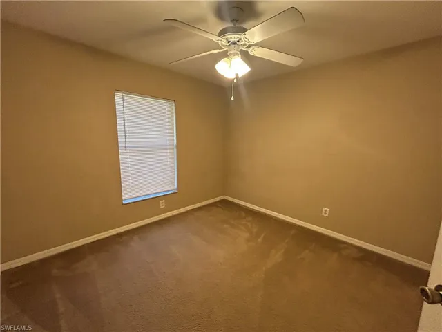 Carpeted spare room with baseboards and ceiling fan