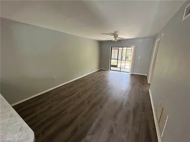 Unfurnished living room with dark wood-style floors and ceiling fan