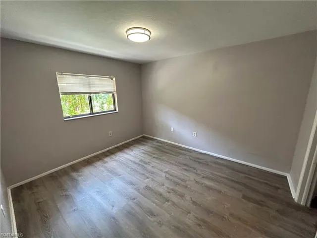 Spare room with dark wood-type flooring and baseboards