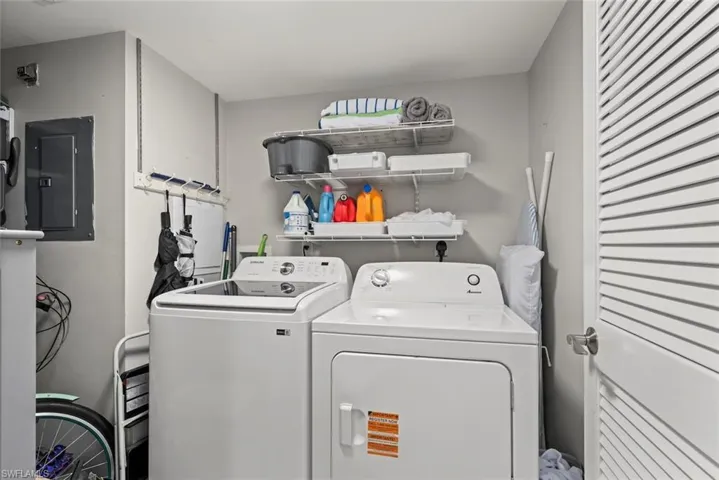 Laundry room with electric panel and washing machine and clothes dryer