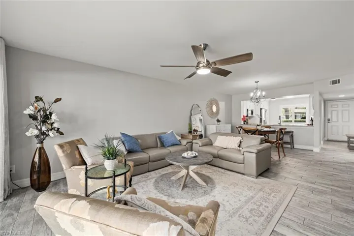 Living room with a ceiling fan, light wood-type flooring, and a chandelier