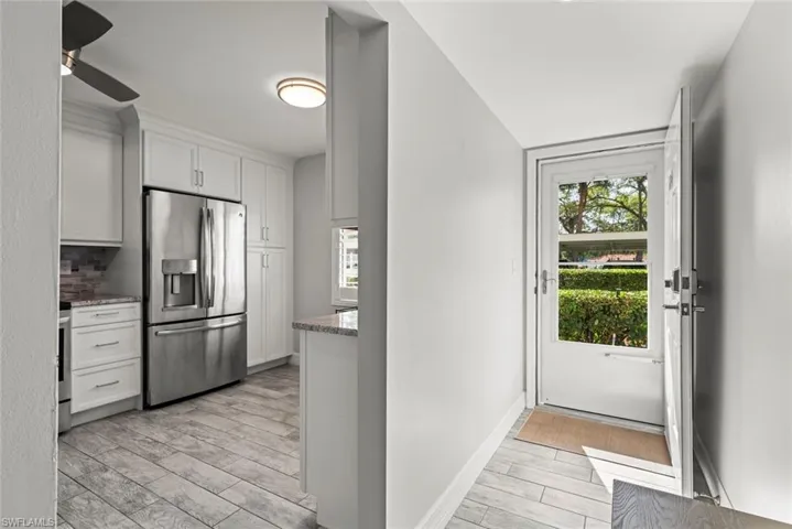 Kitchen with wood finish floors, stainless steel fridge, white cabinets, a ceiling fan, and healthy amount of natural light