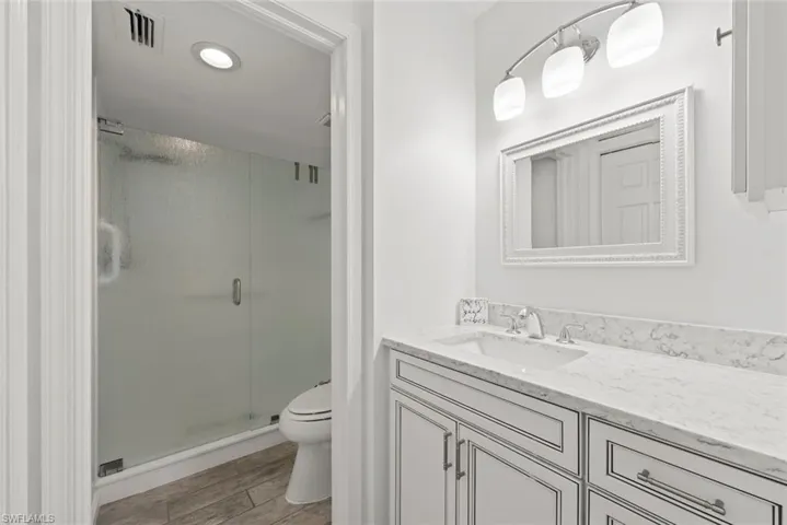 Full bathroom featuring vanity, a stall shower, light wood finished floors, and recessed lighting