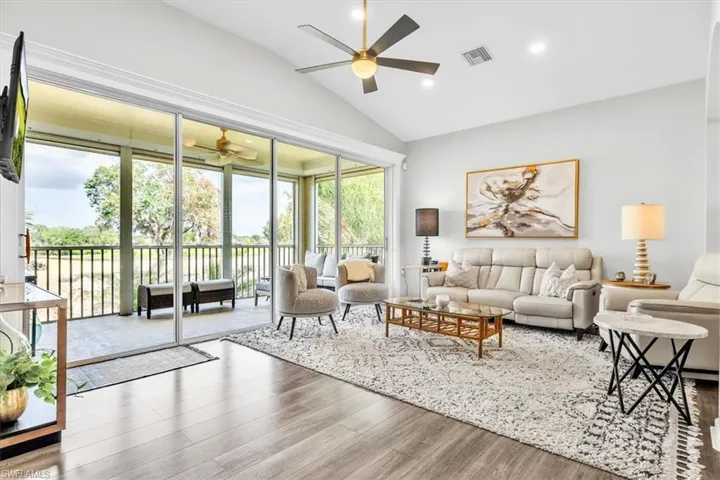 Living area featuring vaulted ceilings, wood-finish flooring, recessed lighting, and a brass-finish ceiling fan