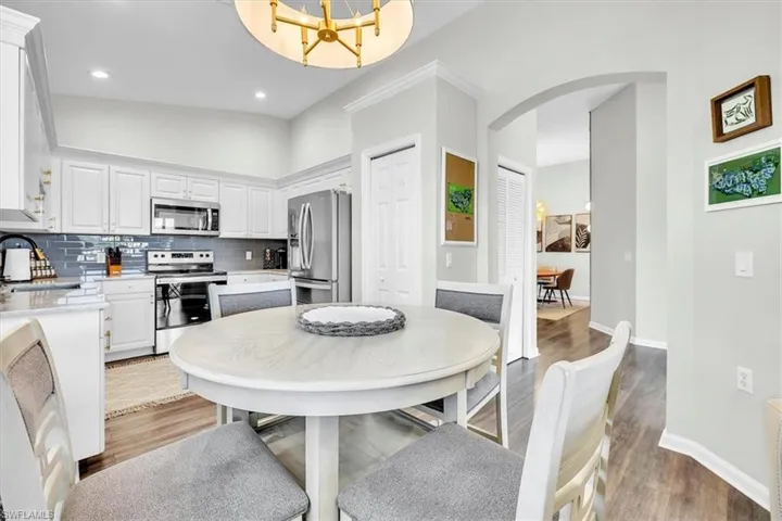 Kitchen dining area featuring a round pedestal table, light wood-finish flooring, and crown molding