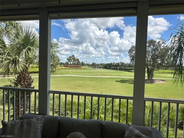 Screened lanai overlooking a golf course with mature palm trees and lush landscaping