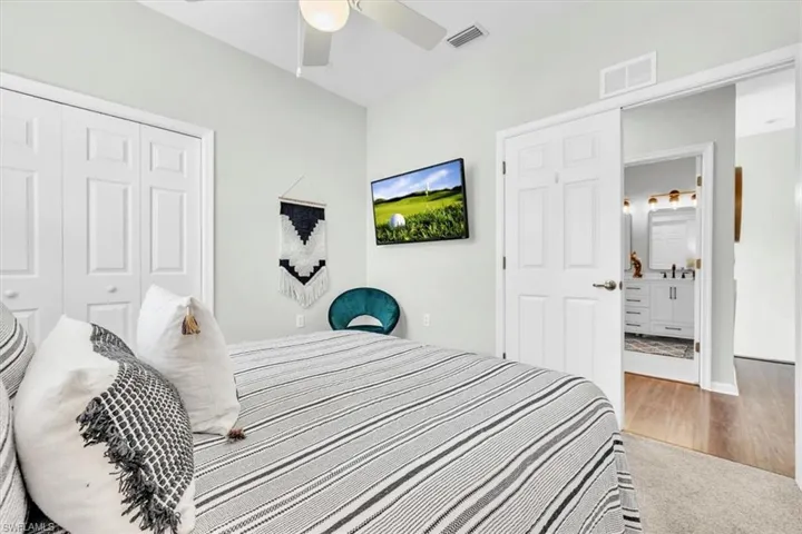 Bedroom featuring a ceiling fan, wall-mounted television, and a double-door closet