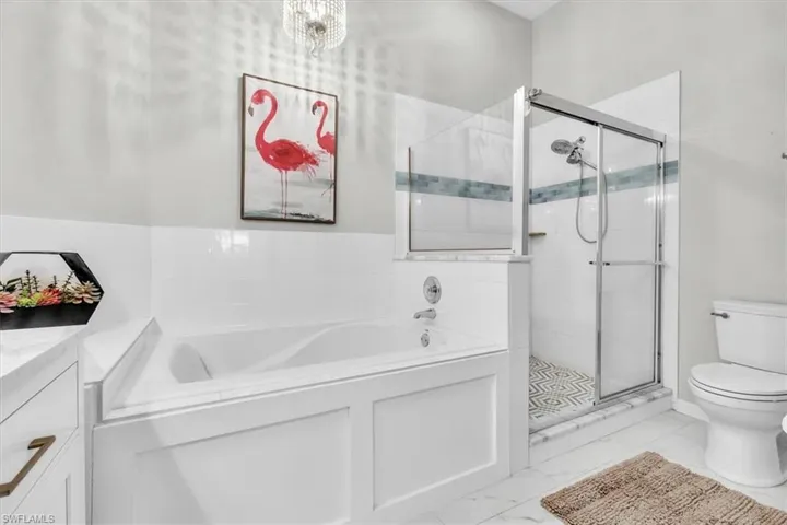Soaking tub with a built-in panel surround, complemented by a glass-enclosed shower with a patterned tile floor