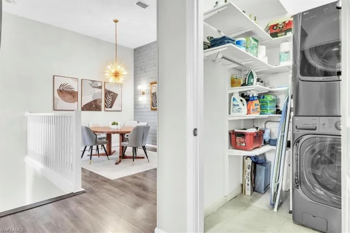 Laundry closet featuring a stacked washer and dryer, tile flooring, and integrated shelving