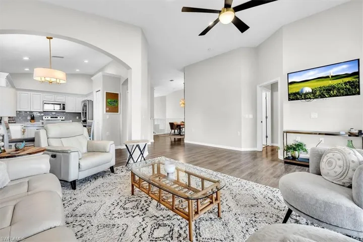 Open-concept living space featuring vaulted ceilings, wood-finish flooring, and an arched entryway