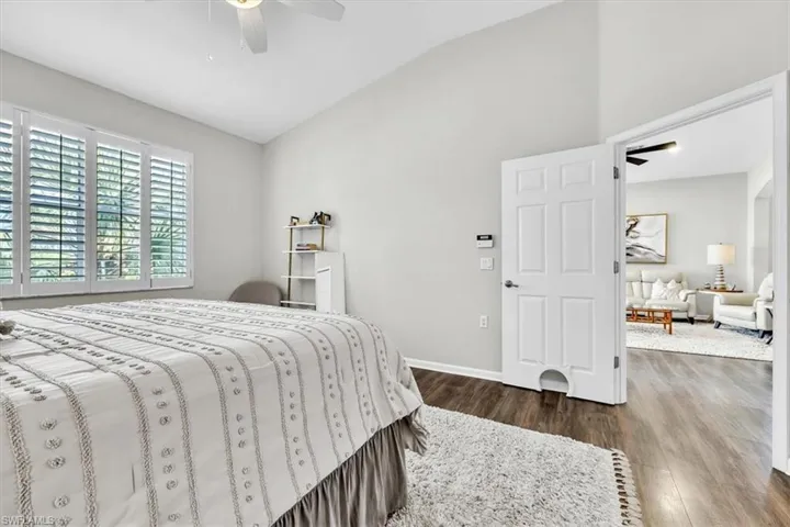 Bedroom featuring vaulted ceilings, wood-finish flooring, and white plantation shutters