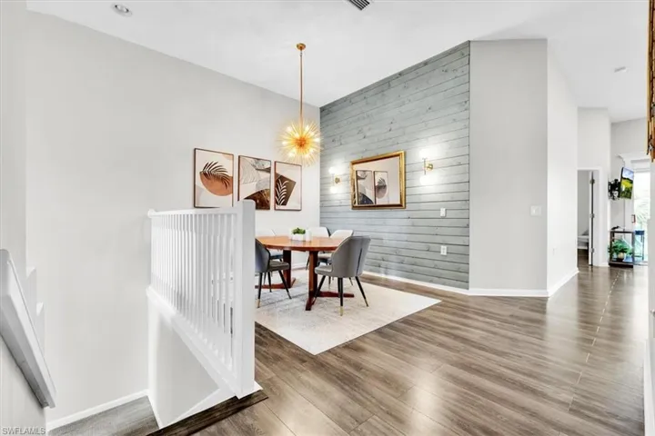 Dining area featuring a shiplap accent wall, wood-finish flooring, and a contemporary chandelier