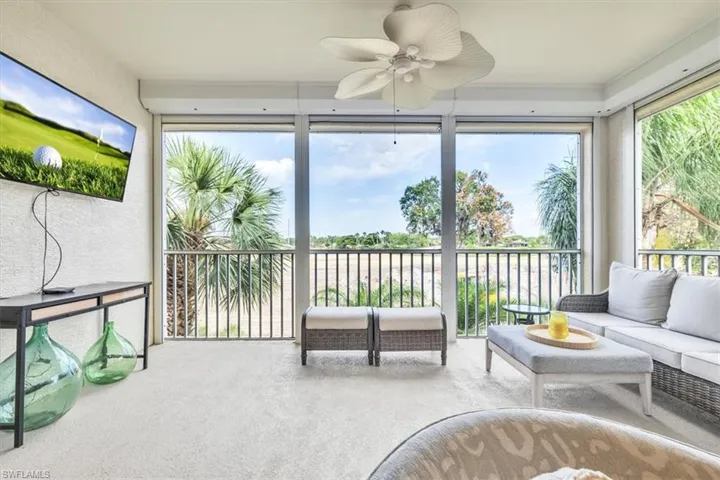 Enclosed balcony featuring light-colored carpeting, a ceiling fan, and large windows with horizontal railings
