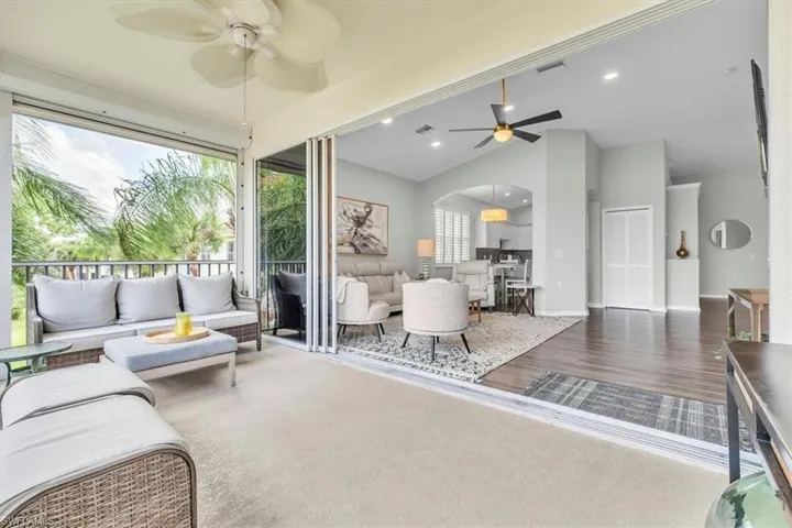 Screened lanai featuring a ceiling fan, outdoor carpeting, and tropical foliage beyond
