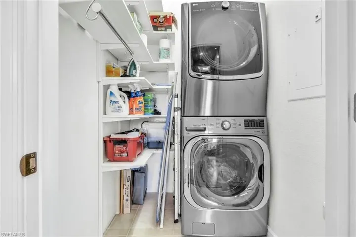 Laundry closet featuring a stacked washer and dryer unit, built-in shelving, and a hanging rod
