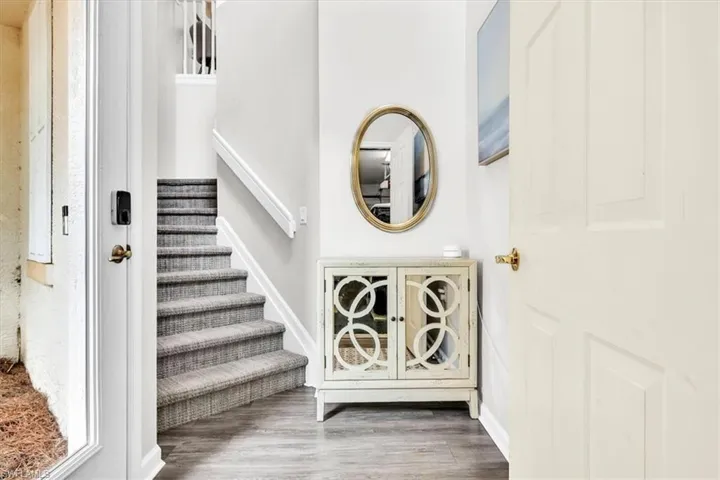 Interior entry with wood-finish flooring, a carpeted staircase, and white trim