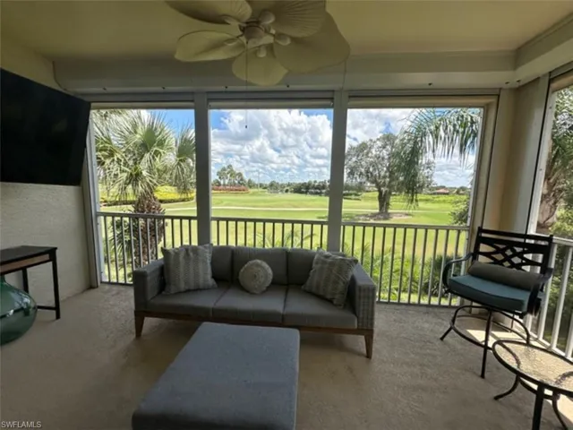 Screened-in patio with light-toned flooring, featuring a ceiling fan and expansive views of a green landscape