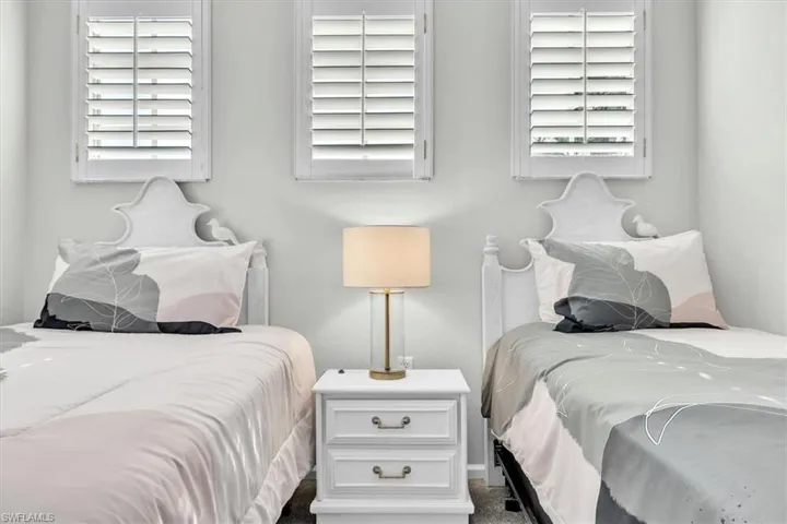 Dual beds with ornate white headboards frame a central nightstand