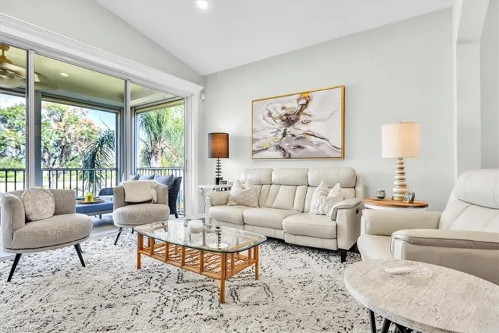 Living area featuring a vaulted ceiling and sliding glass doors opening to an outdoor screened lanai