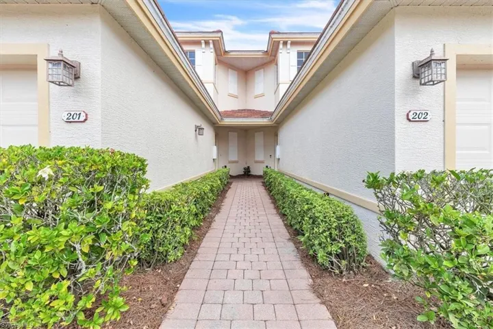 Paver pathway entryway flanked by manicured shrubbery