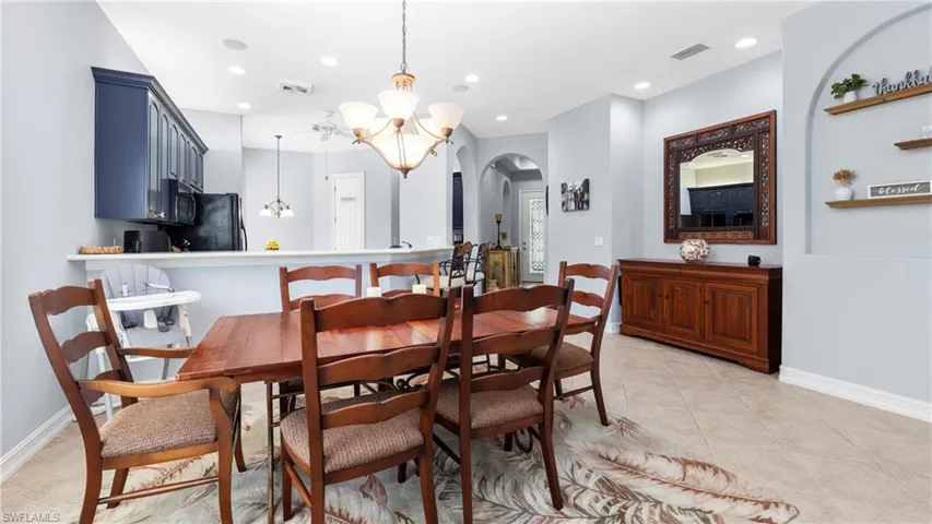 Dining space featuring suspended lighting, arched walkways, and light tile patterned floors