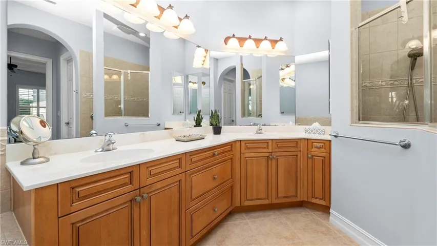 Full bathroom featuring double vanity, a stall shower, and light tile patterned floors