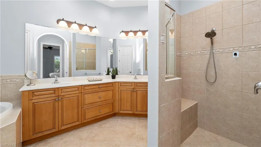 Ensuite bathroom with walk in shower, double vanity, light tile patterned floors, and a bath
