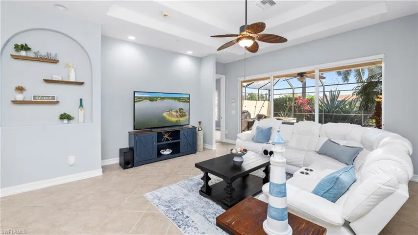 Living room featuring a sunroom, a tray ceiling, light tile patterned floors, ceiling fan, and recessed lighting