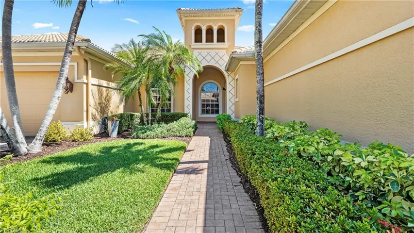View of exterior entry with stucco siding, a yard, and a tile roof