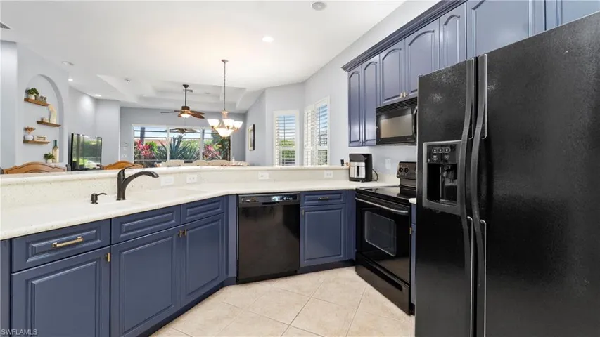 Kitchen featuring black appliances, blue cabinetry, light tile patterned floors, suspended lighting, and a ceiling fan