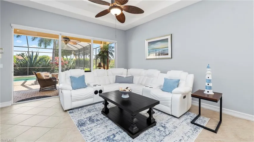 Living room featuring a sunroom, a ceiling fan, light tile patterned flooring, and a tray ceiling