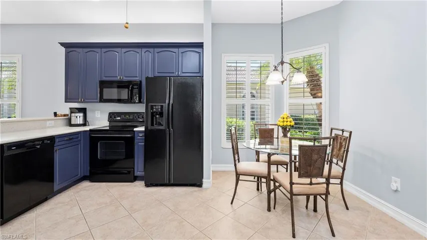 Kitchen with black appliances, light countertops, blue cabinetry, and light tile patterned flooring