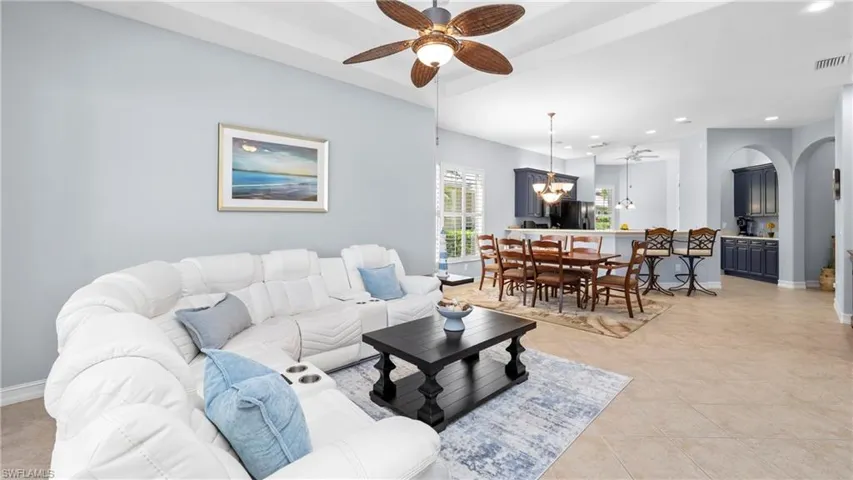 Living area featuring ceiling fan, light tile patterned floors, and a chandelier