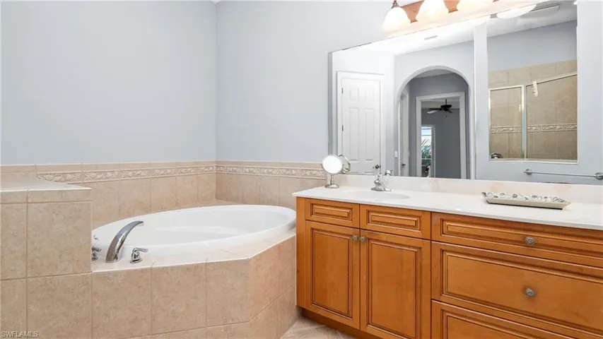 Bathroom with vanity, a garden tub, a shower stall, and ceiling fan
