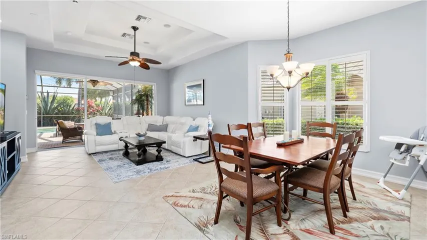Dining room featuring hanging lights, ceiling fan, a sunroom, light tile patterned floors, and a tray ceiling