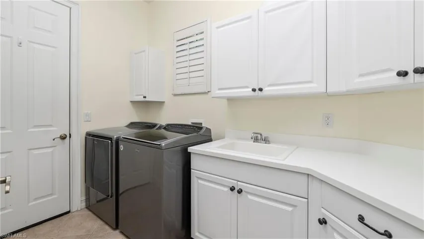 Laundry area featuring cabinet space, light tile patterned floors, and washer and clothes dryer