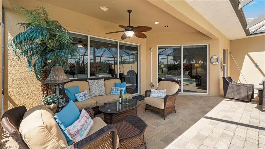 View of patio with outdoor seating, a ceiling fan, and glass enclosure