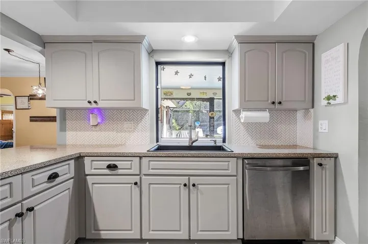Kitchen with gray cabinets, tasteful backsplash, kitchen peninsula, sink, and stainless steel dishwasher