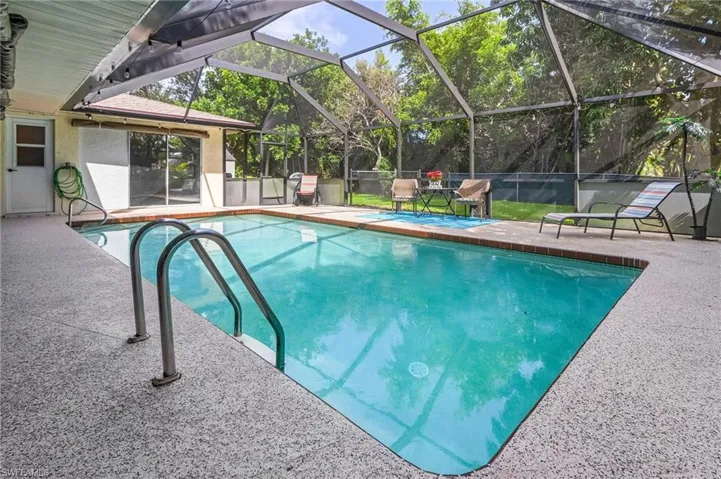 View of swimming pool with screen enclosure and a patio area