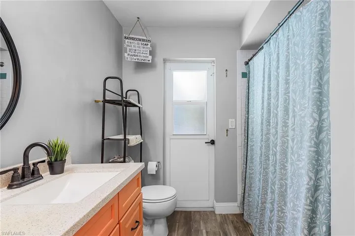 Bathroom featuring a shower with curtain, wood-type flooring, toilet, and vanity,Access to the pool