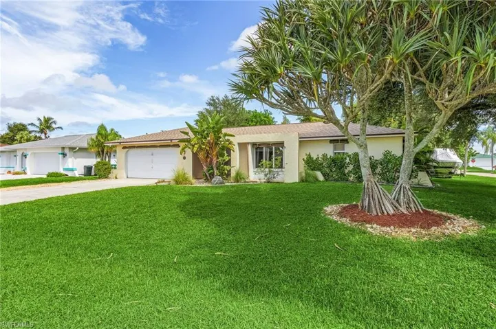 Ranch-style home featuring a garage and a front lawn