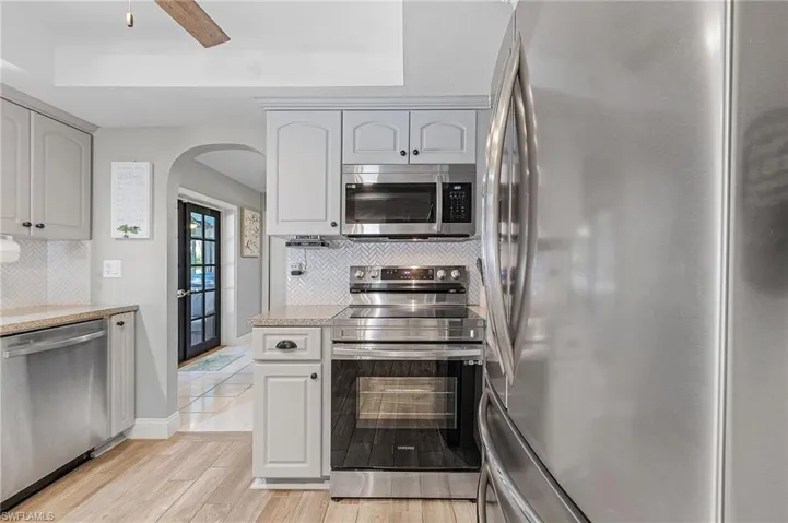 Kitchen with appliances with stainless steel finishes, decorative backsplash, light hardwood / wood-style floors, and ceiling fan