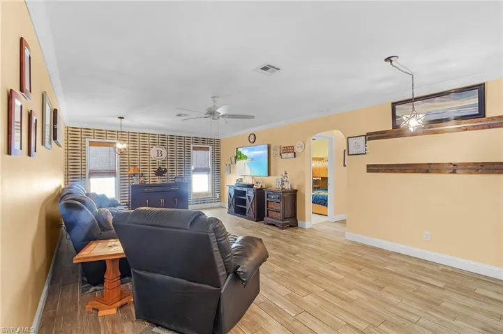Living room with ceiling fan, crown molding, and wood-type flooring